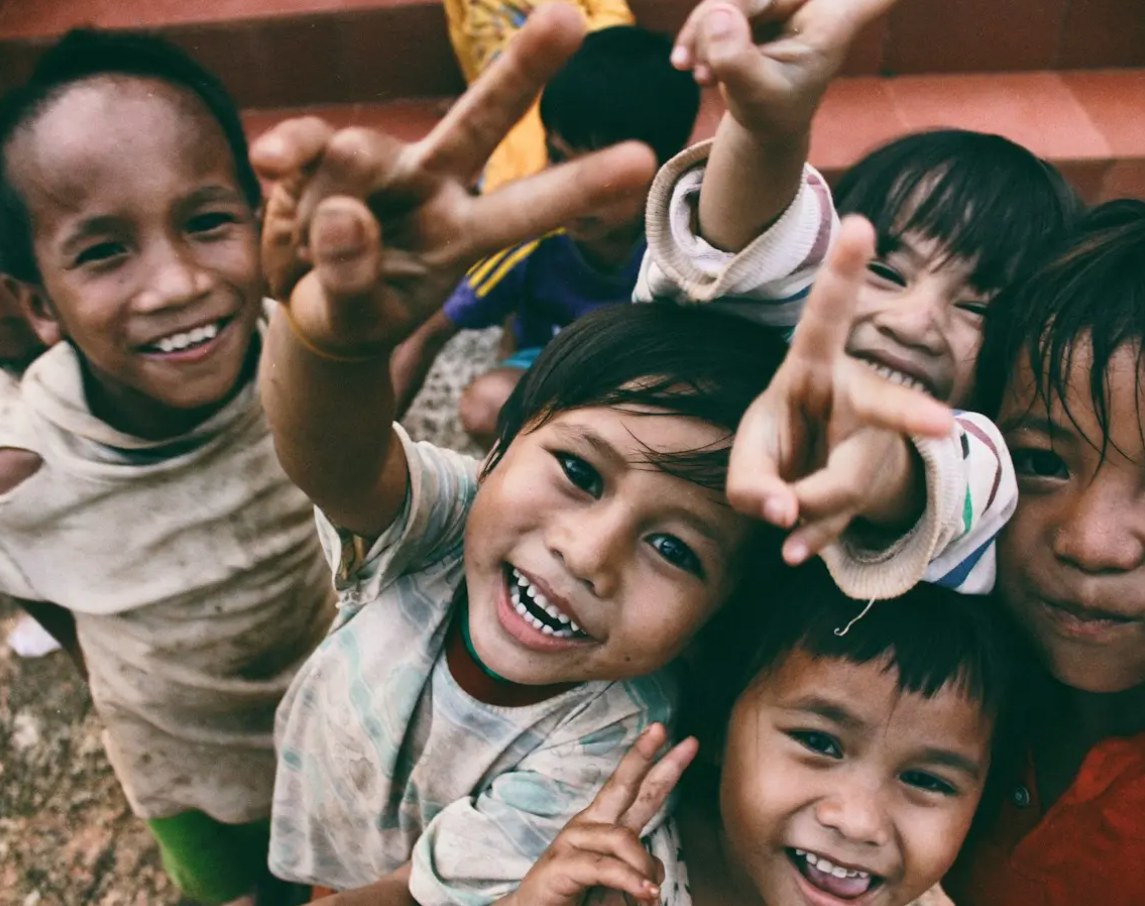 Children smiling and reaching toward the camera